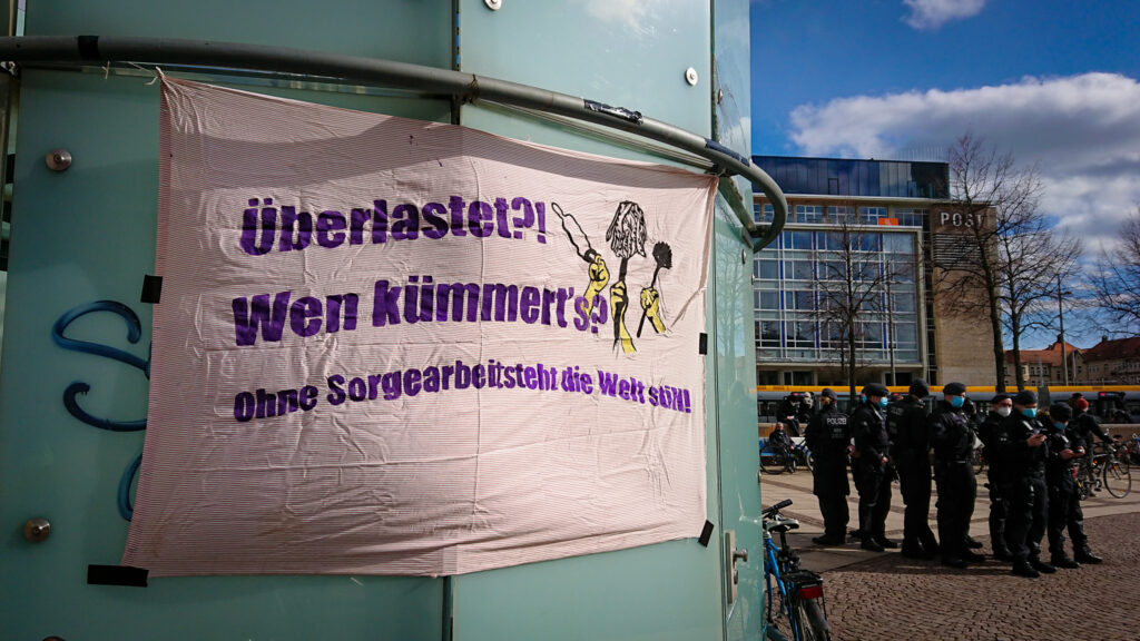 Ein Transparent mit der Aufschrift "Überlastet?! Wen kümmert's? Ohne Sorgearbeit steht die Welt still!" auf der Kundgebung für Gesundheit und Feminismus in Leipzig