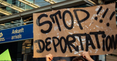 Beim Protest gegen die Abschiebung am Leipiger Flughafen hält eine Person ein Schild mit der Aufschrift "Stop Deportation" vor dem Ankunftsterminal in die Höhe