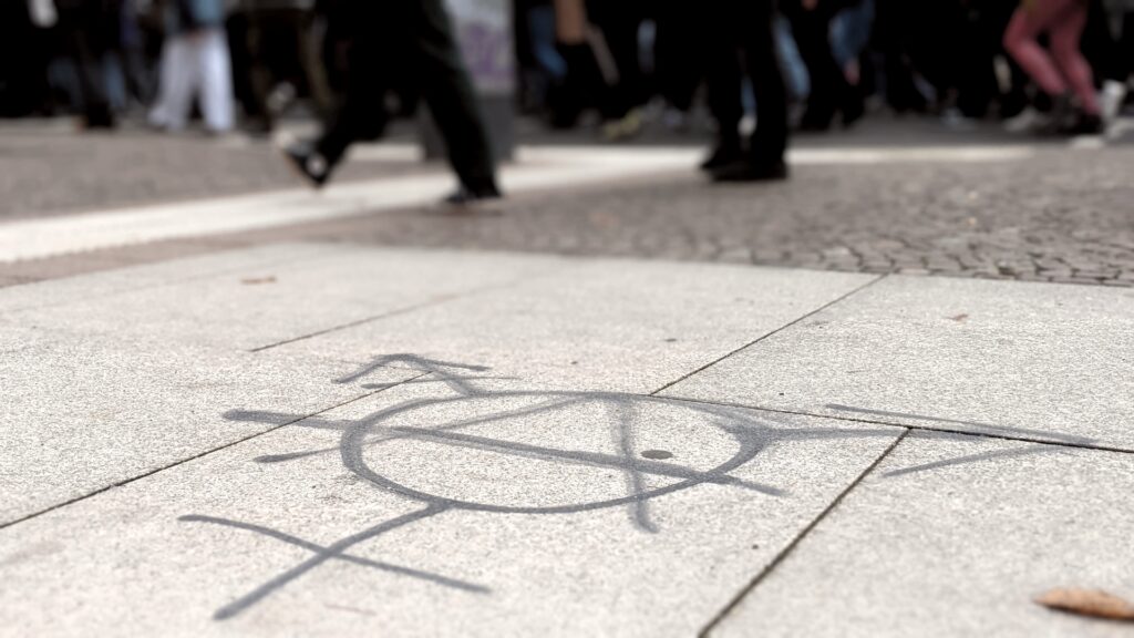 Foto: Grafitti auf dem Boden mit Menschen im Hintergrund