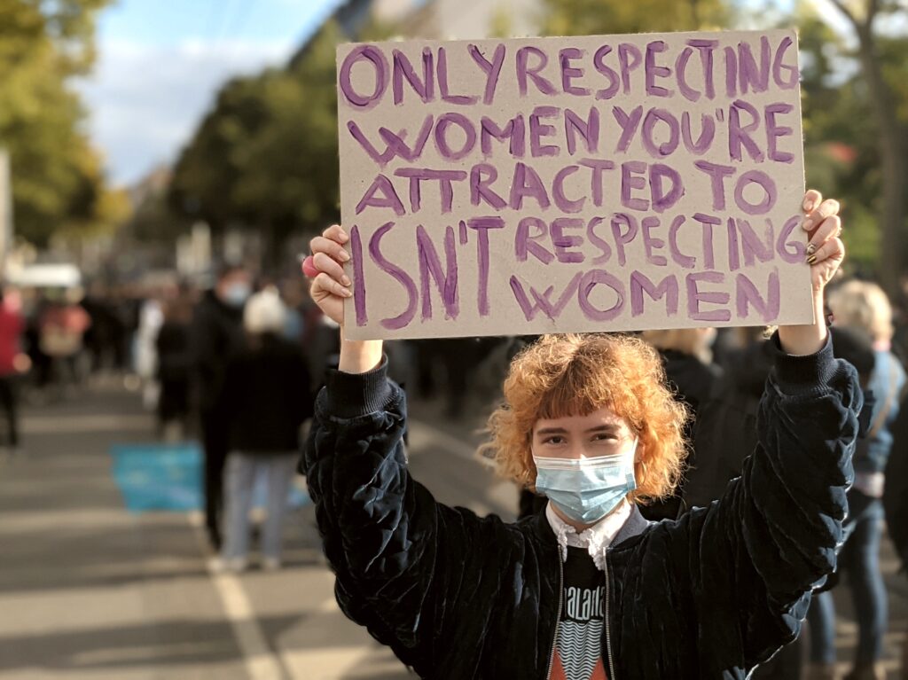 Eine Person hält ein Schild in die Luft: "Only respecting women you're attracted to isn't respecting women"